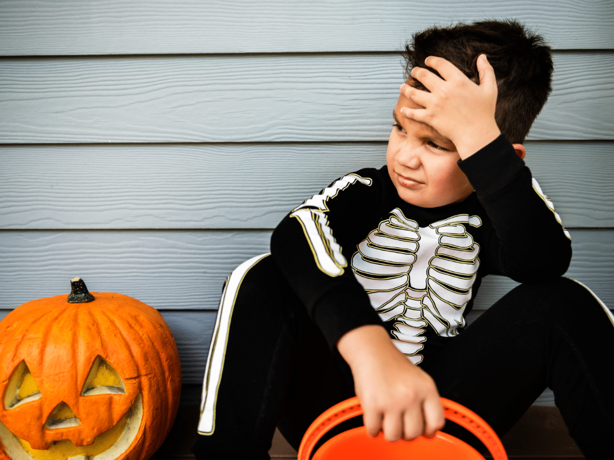 A boy sits to rest after visiting houses for trick-or-treating