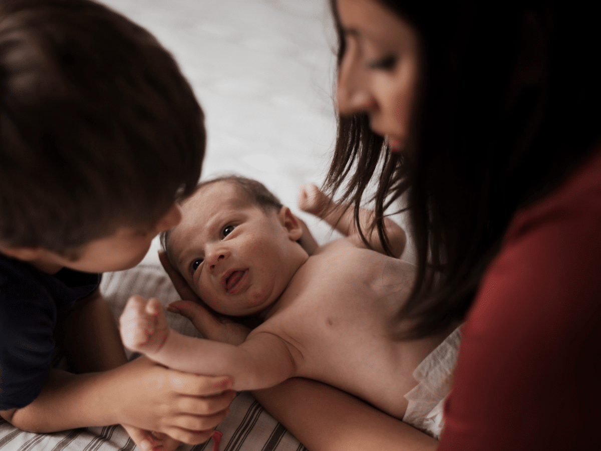 A mother and son engage in infant bonding with the newest member of the family.