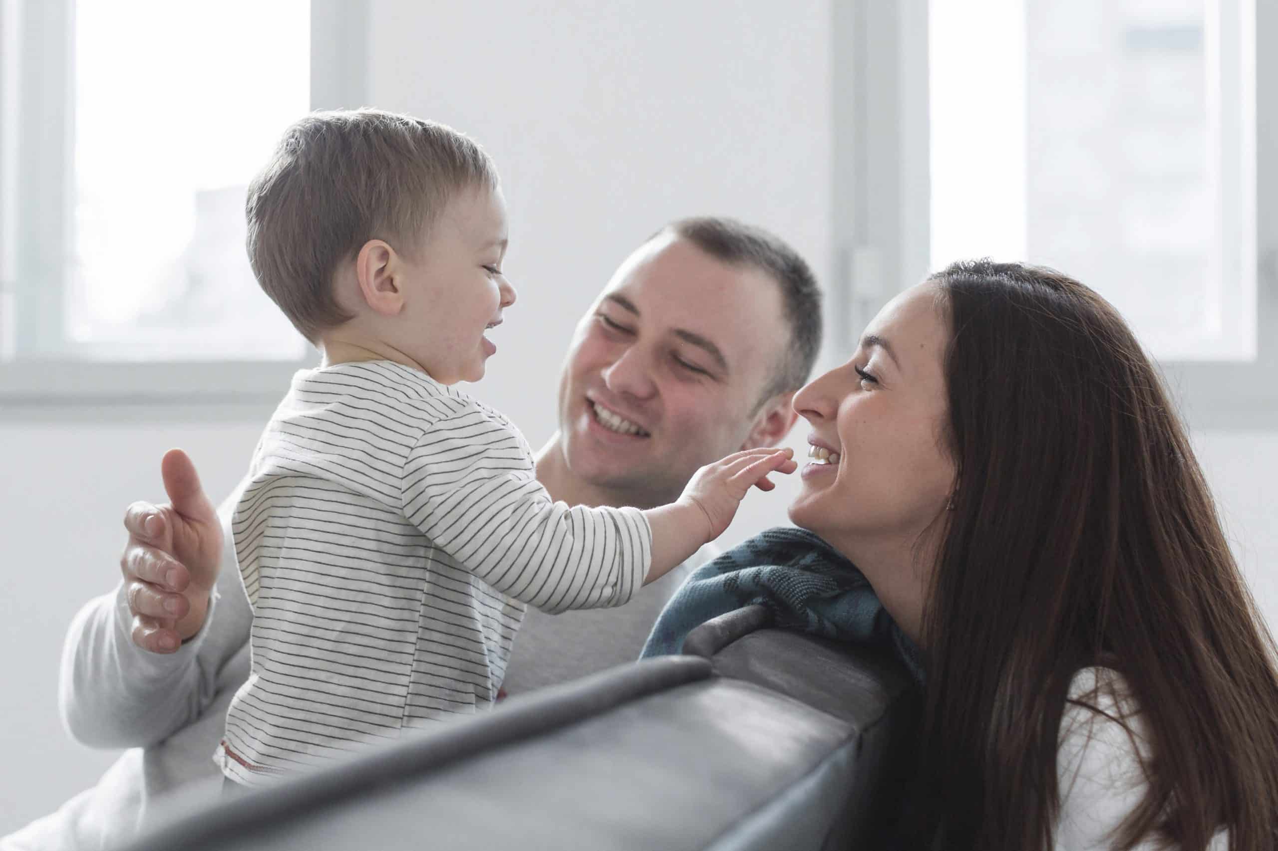 A toddler who has just completed their childhood immunizations happily plays with their parents. 