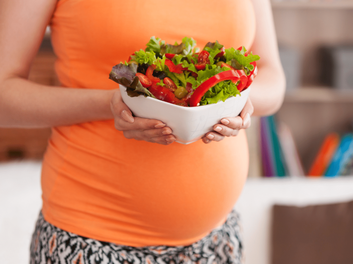 Pregnant woman holds a nutritious salad