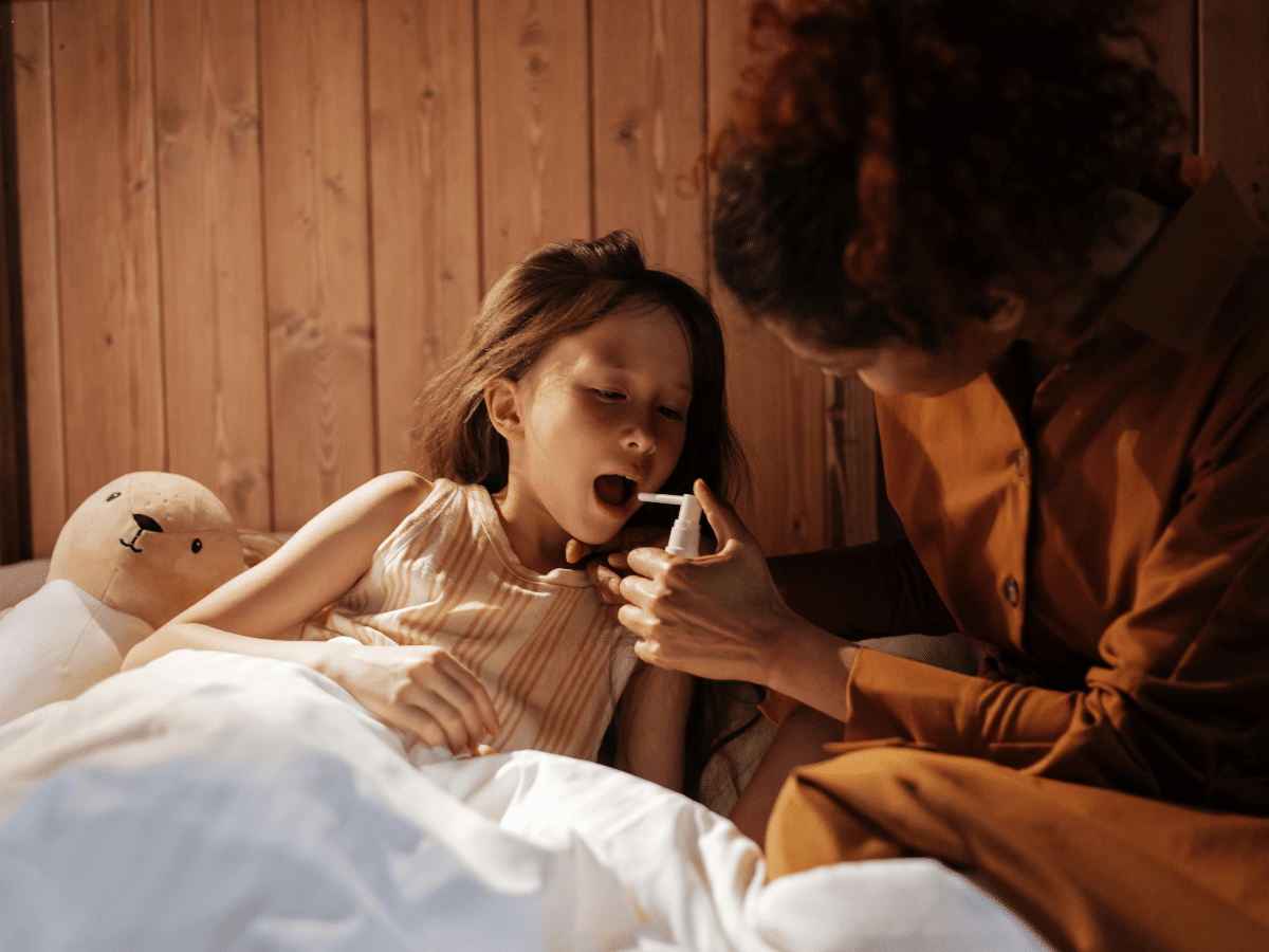 A mother helping her daughter take her throat medication