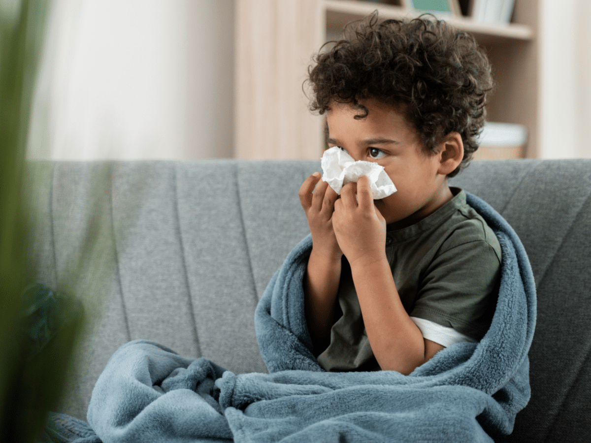 A child shows symptoms of pediatric flu, including a runny nose and difficulty breathing.
