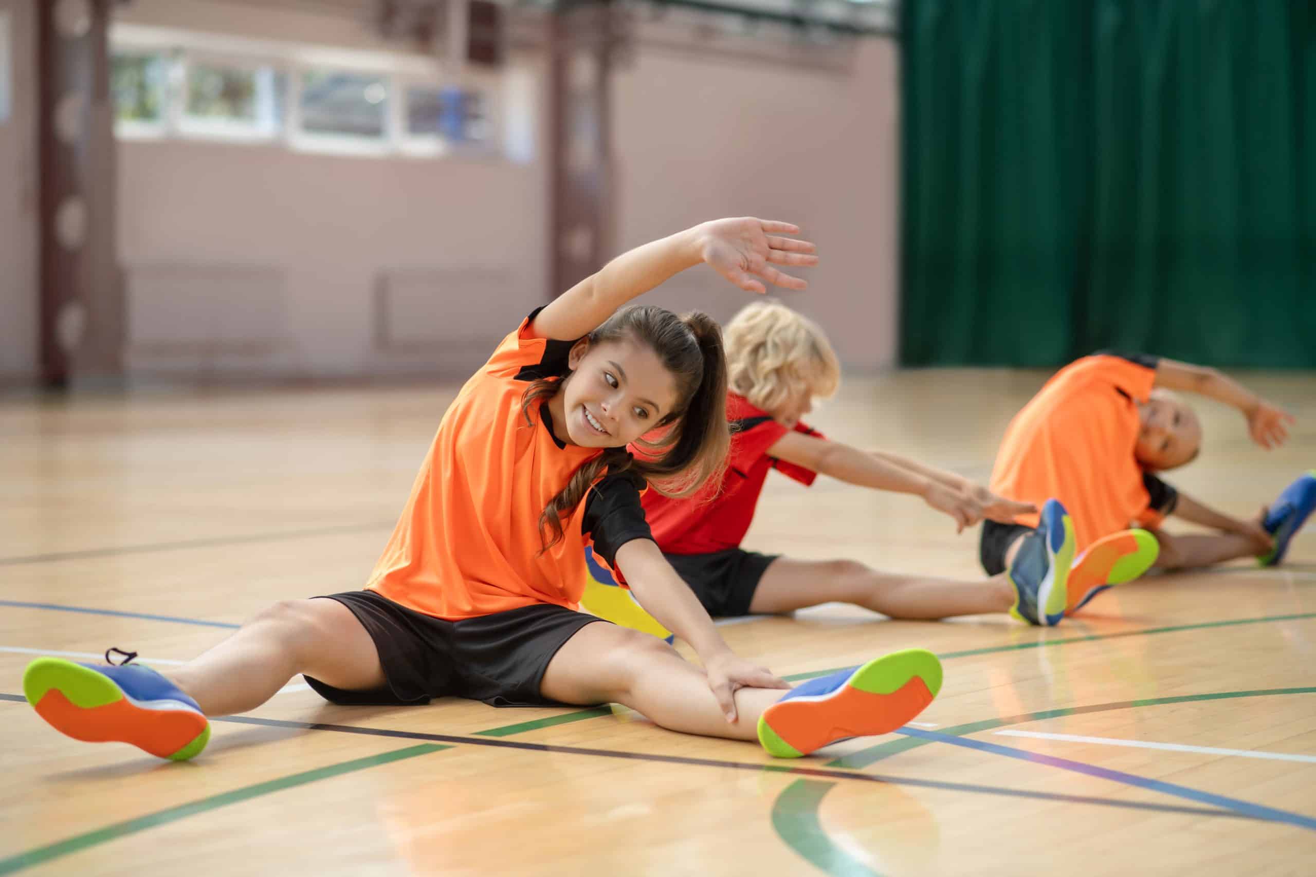 A child confidently does warm-up exercises after their athletic physical exam appointment.