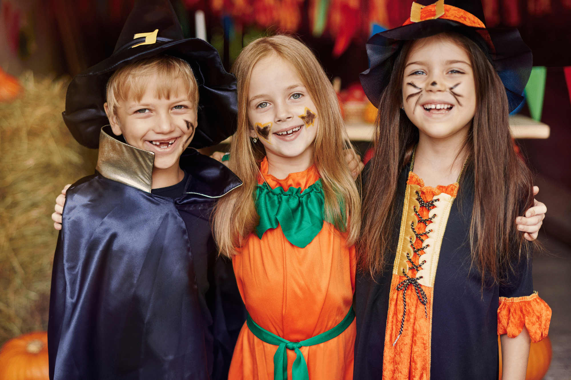 Three smiling children in costumes posing together, ready for a fun and safe Halloween night celebration