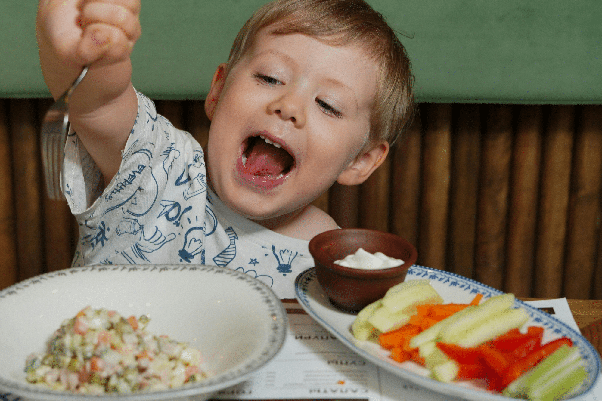 A young boy enjoys a healthy diet, which includes fresh vegetables and fruits.