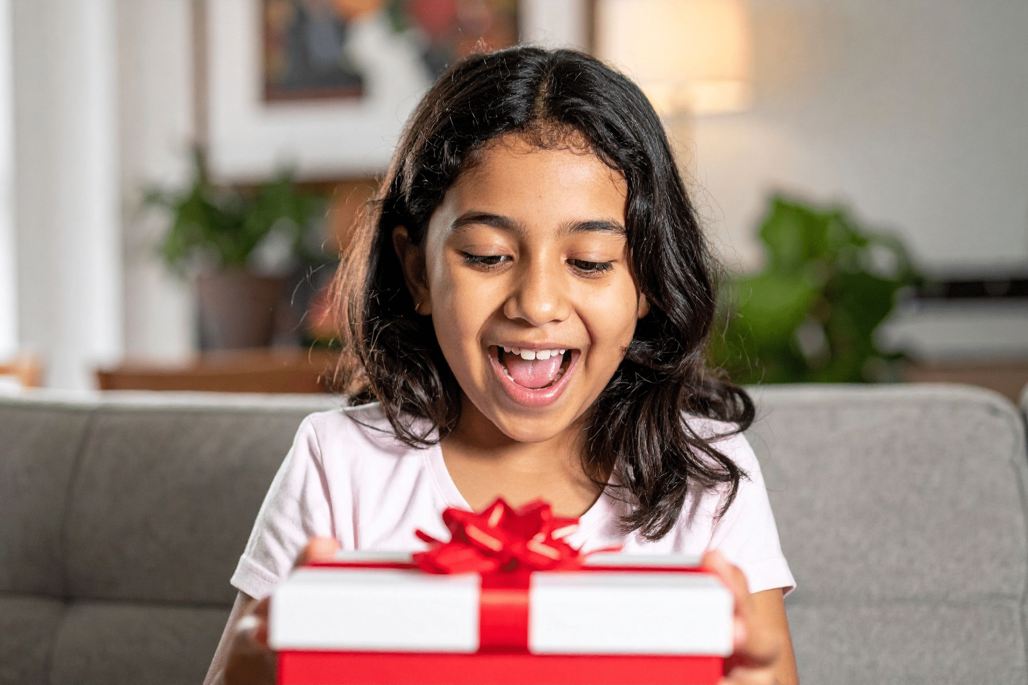 A little girl happily receives a gift with the holiday toys she wished for.