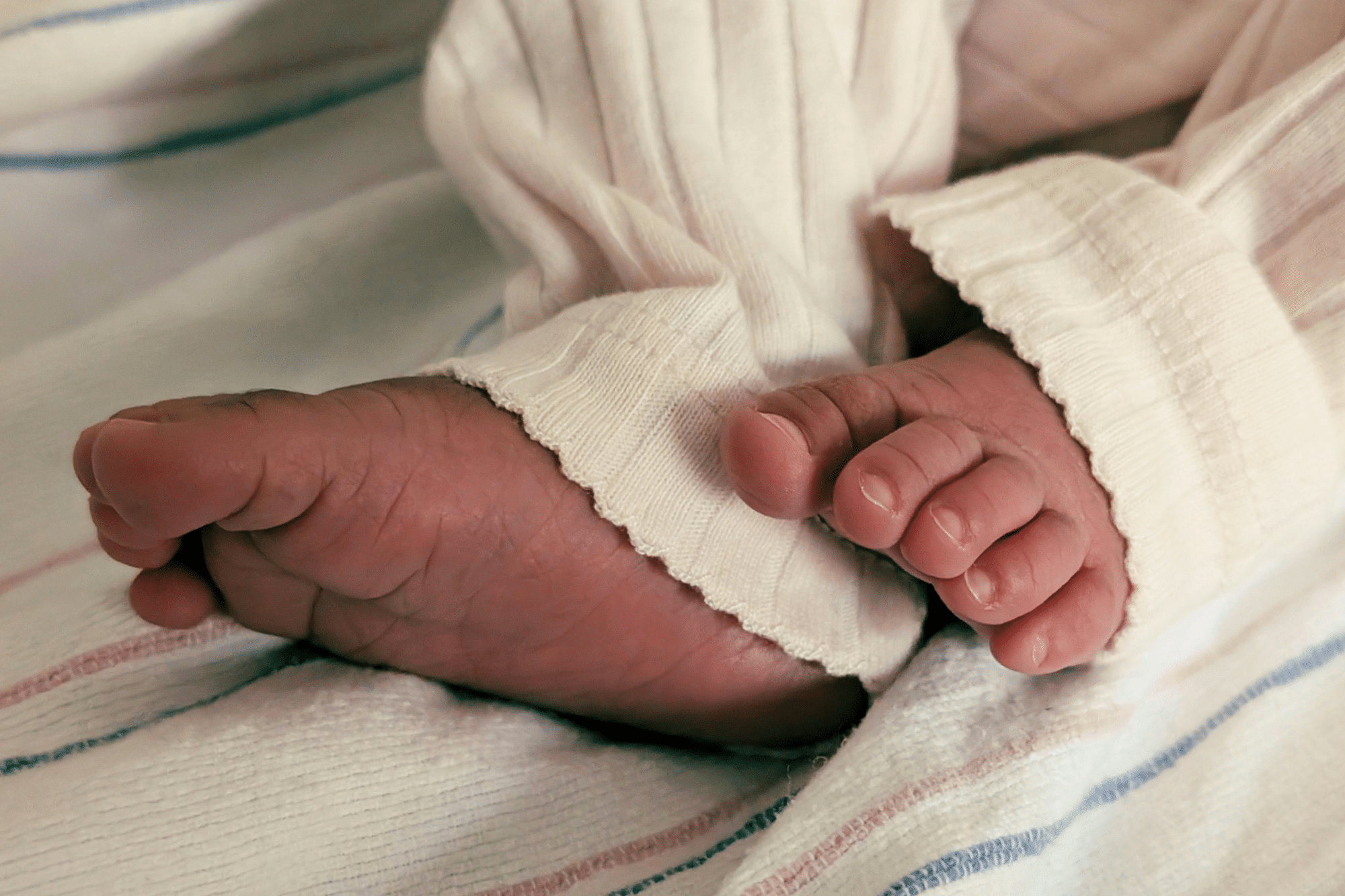 Newborn’s curled feet in soft fabric, emphasizing safe and nurturing newborn infant care.