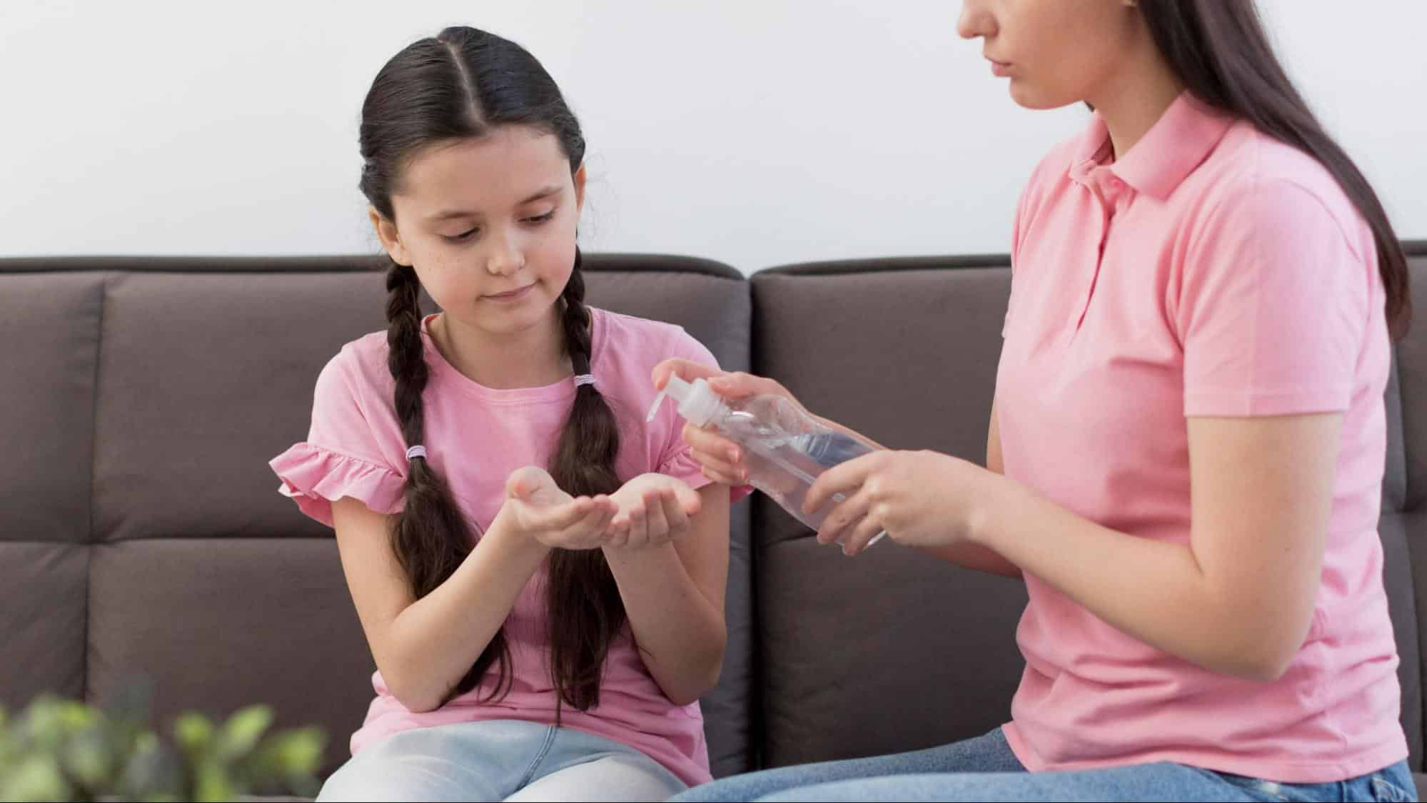 A mother pours sanitizer into their child’s hands, one of the first aid kit supplies they prepared at home.