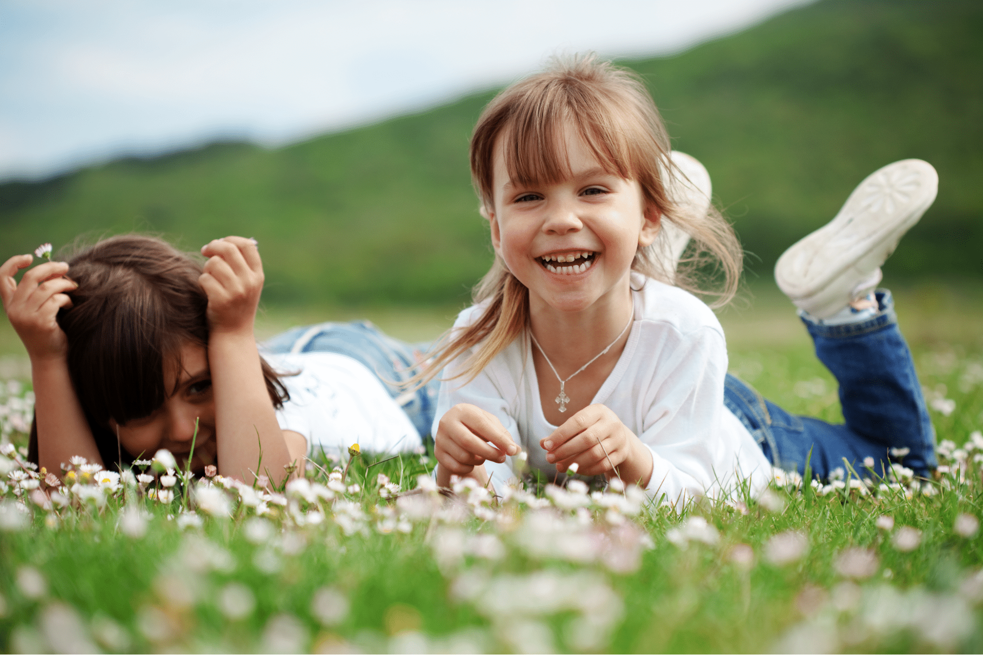 Two children lying in a blooming flower field, smiling and relaxed, showing healthy kids during the spring allergy season.