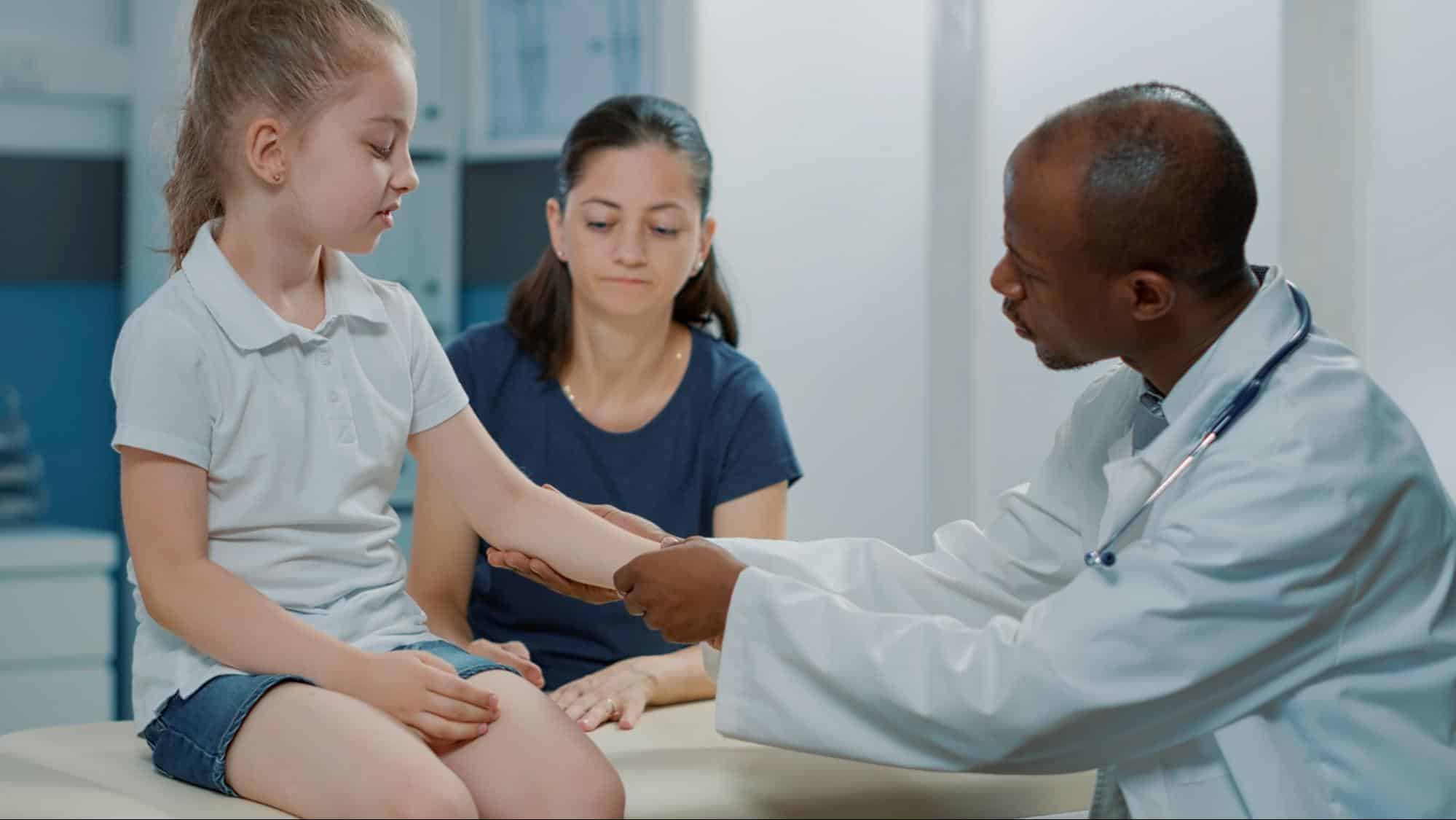 Pediatrician checking a child's arm during pediatric fracture recovery